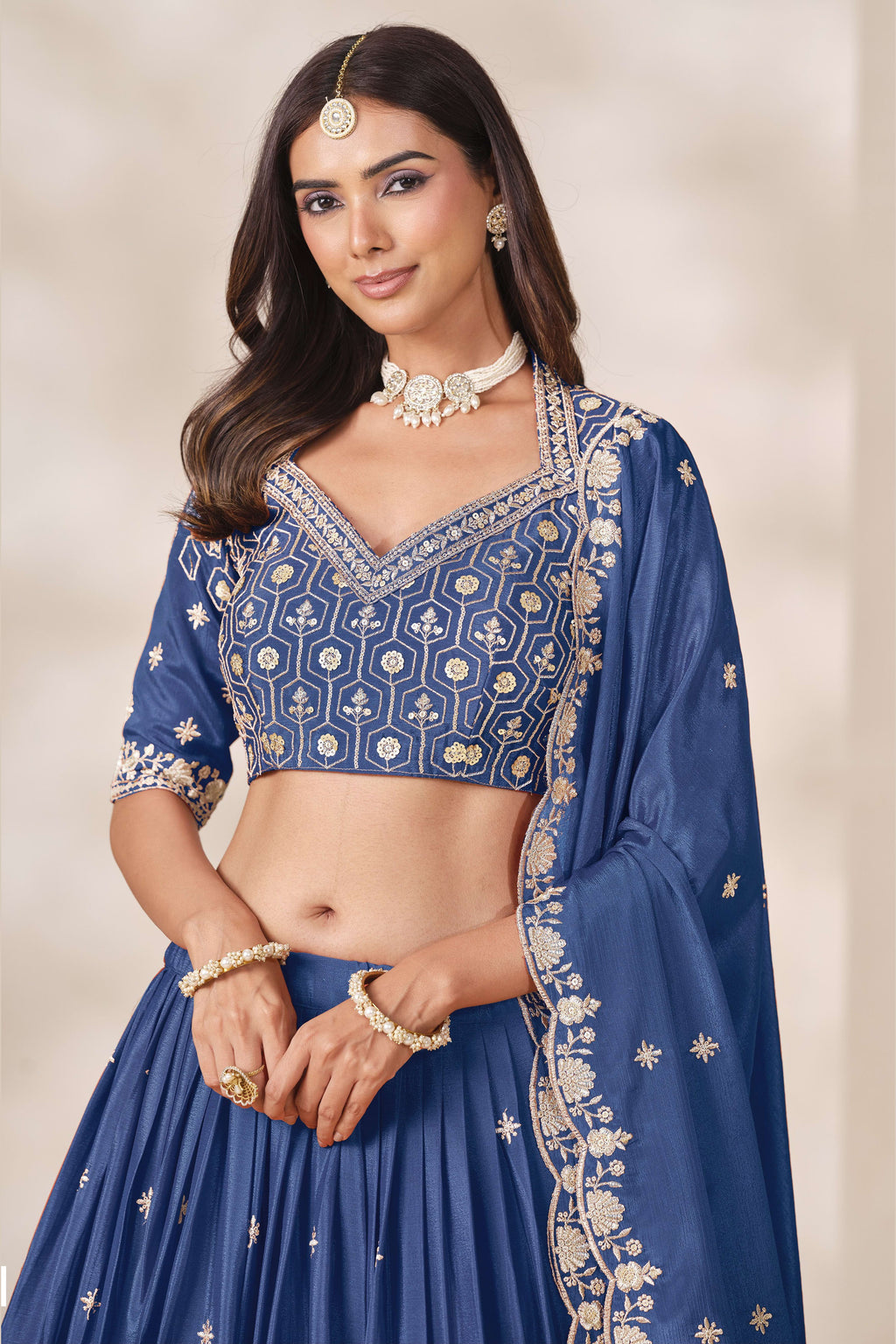 Close-up of a dusty blue engagement lehenga blouse in chinon silk with sequin and thread embroidery on the V neckline and elbow sleeves.