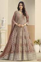 Woman wearing a traditional brown and beige embroidered dress in an indoor setting.
