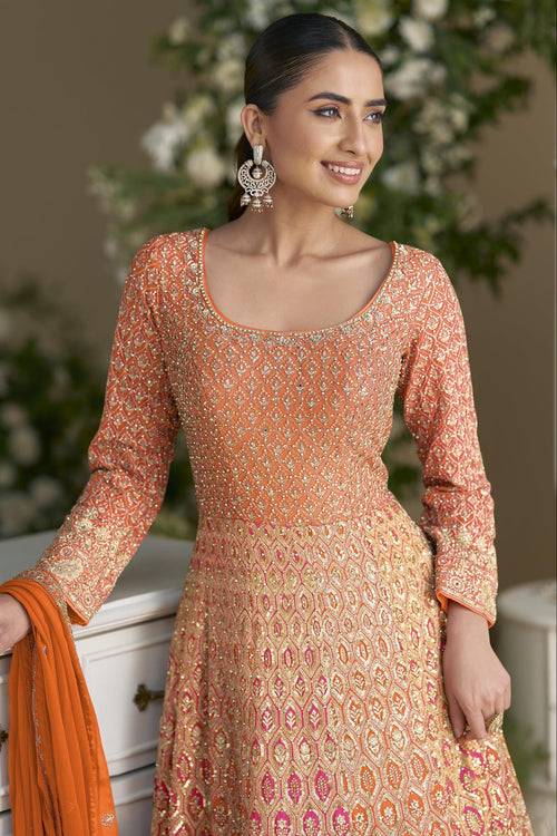 A waist-up view of a model in an orange georgette anarkali suit, showing the wide U neckline, geometric sequin work and full sleeves, with an orange dupatta in hand.