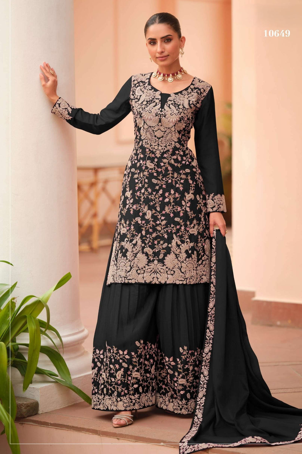 Woman wearing a black plazo dress in chinon silk with thread embroidery work, paired with an embroidered plazo and dupatta, full-length front view.
