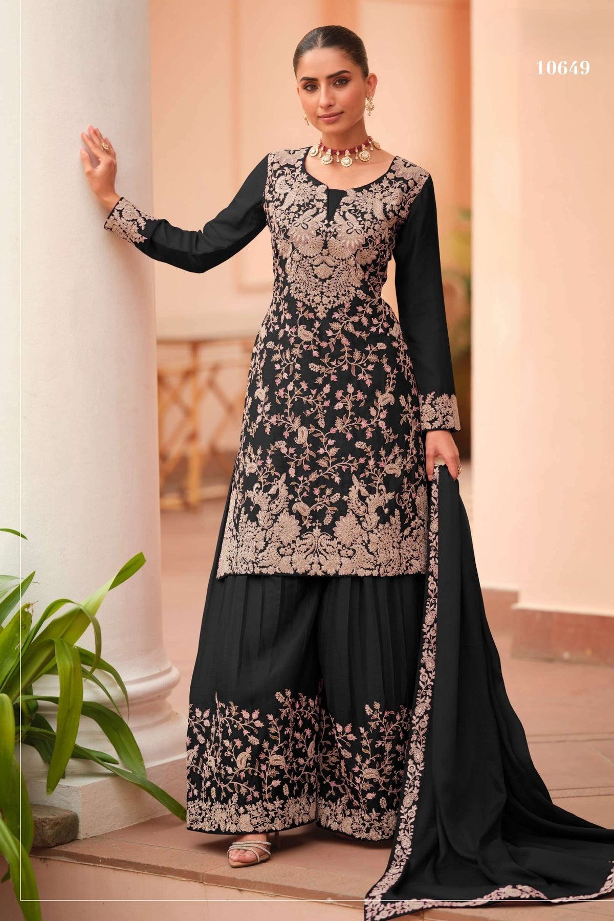 Woman wearing a black plazo dress in chinon silk with thread embroidery work, paired with an embroidered plazo and dupatta, full-length front view.