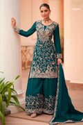 Woman wearing a teal palazzo suit in chinon silk with thread embroidery work, paired with an embroidered plazo and dupatta, full-length front view.