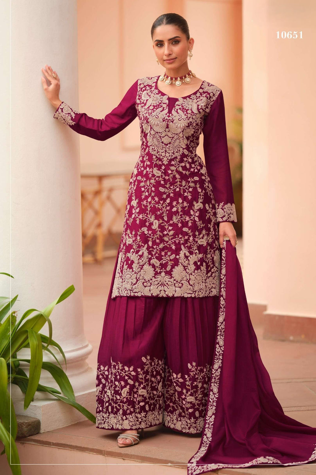 Woman wearing a maroon palazzo dress in chinon silk with thread embroidery work, paired with an embroidered plazo and dupatta, full-length front view.