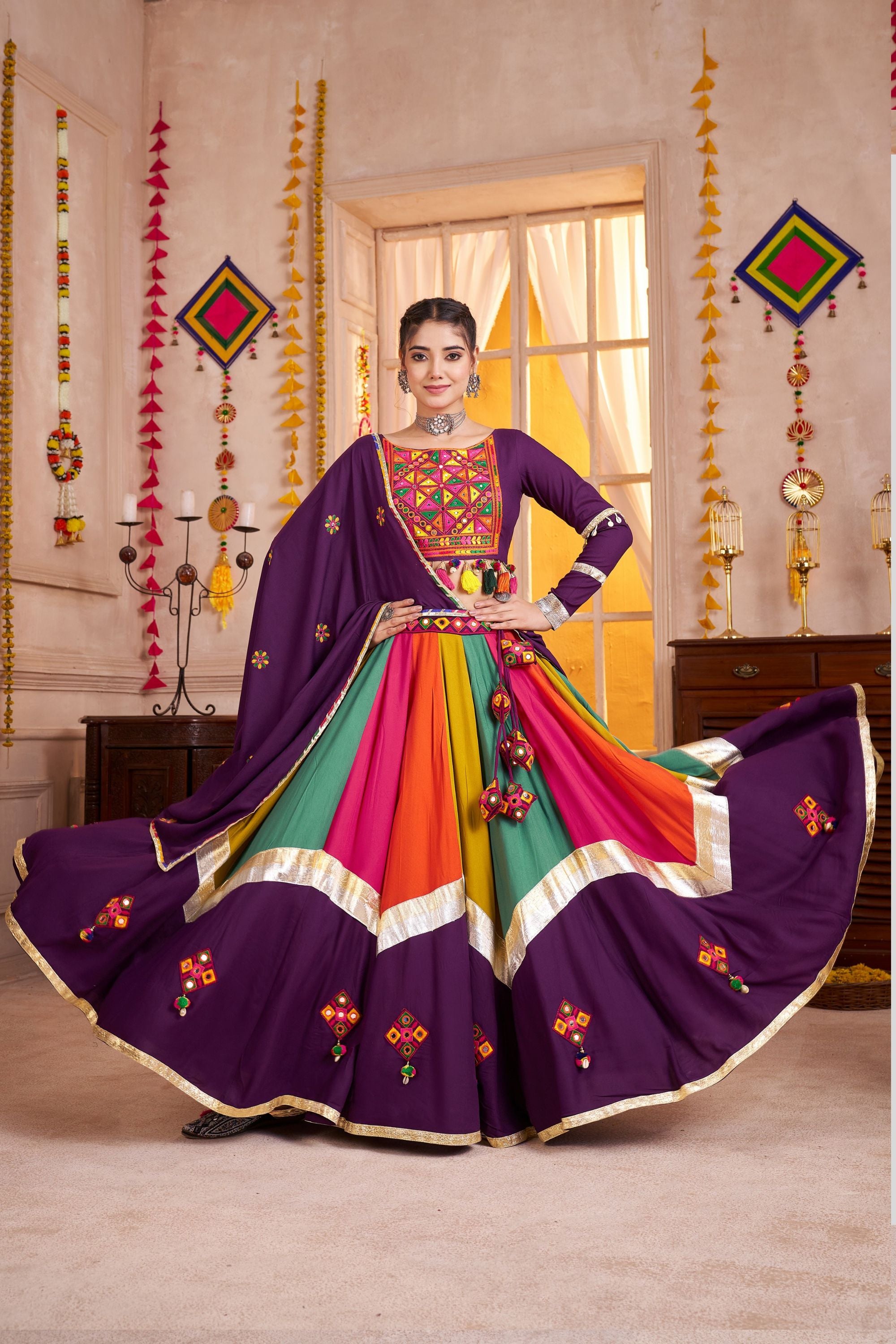Colorful traditional outfit with a purple dupatta in a decorated room.