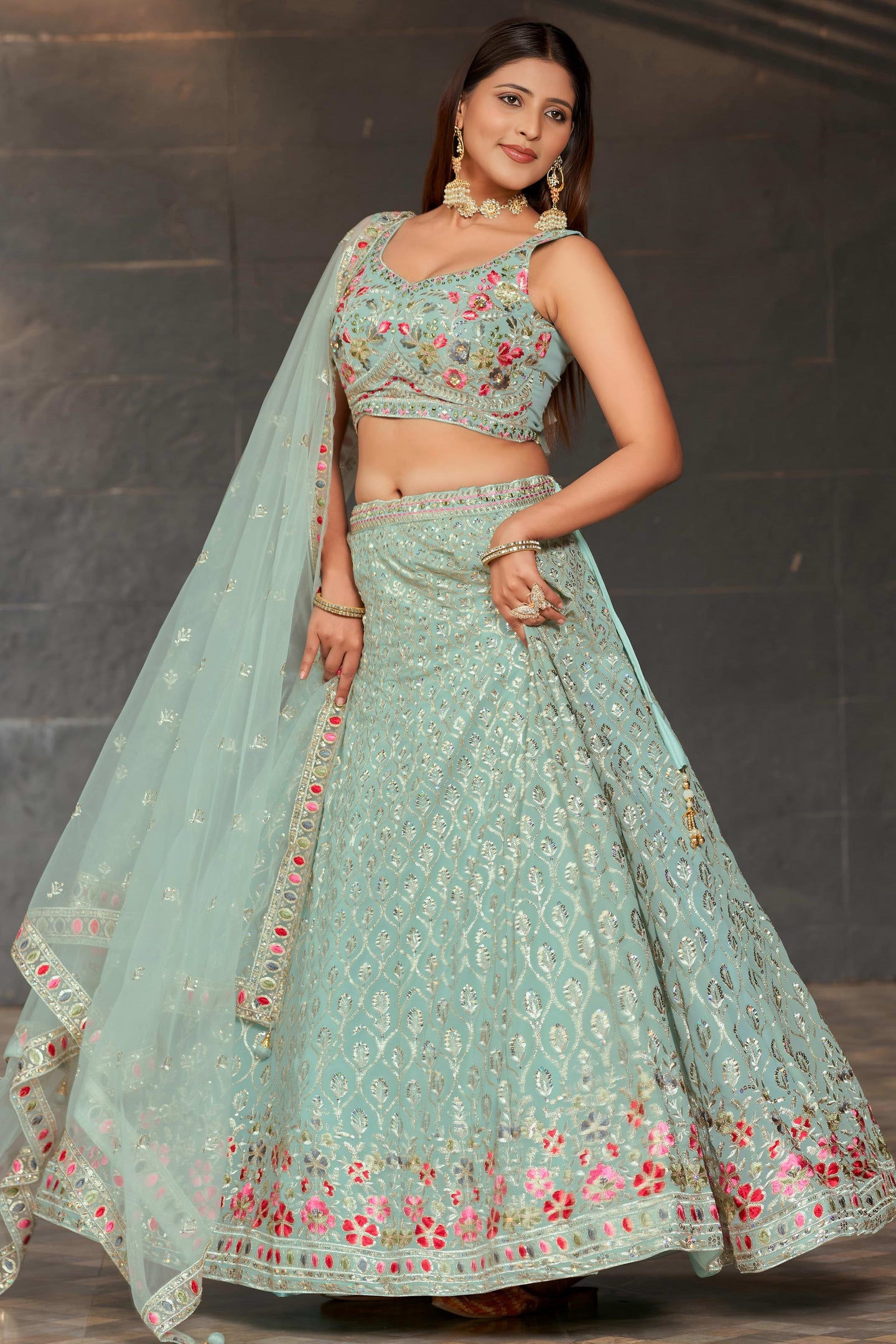 Woman wearing a light blue embroidered traditional outfit with a dark background