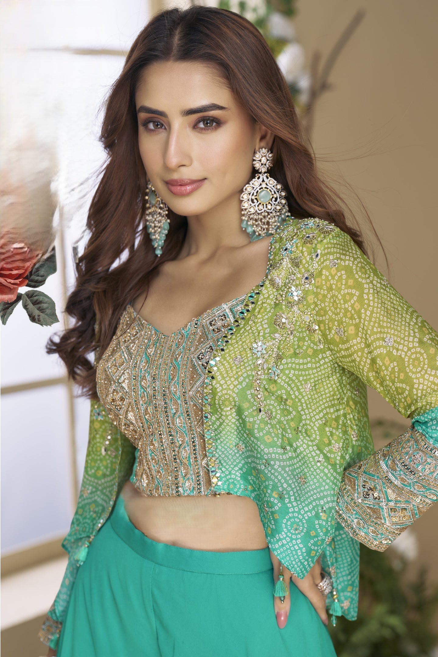 Woman wearing a teal and gold traditional outfit with jewelry indoors.