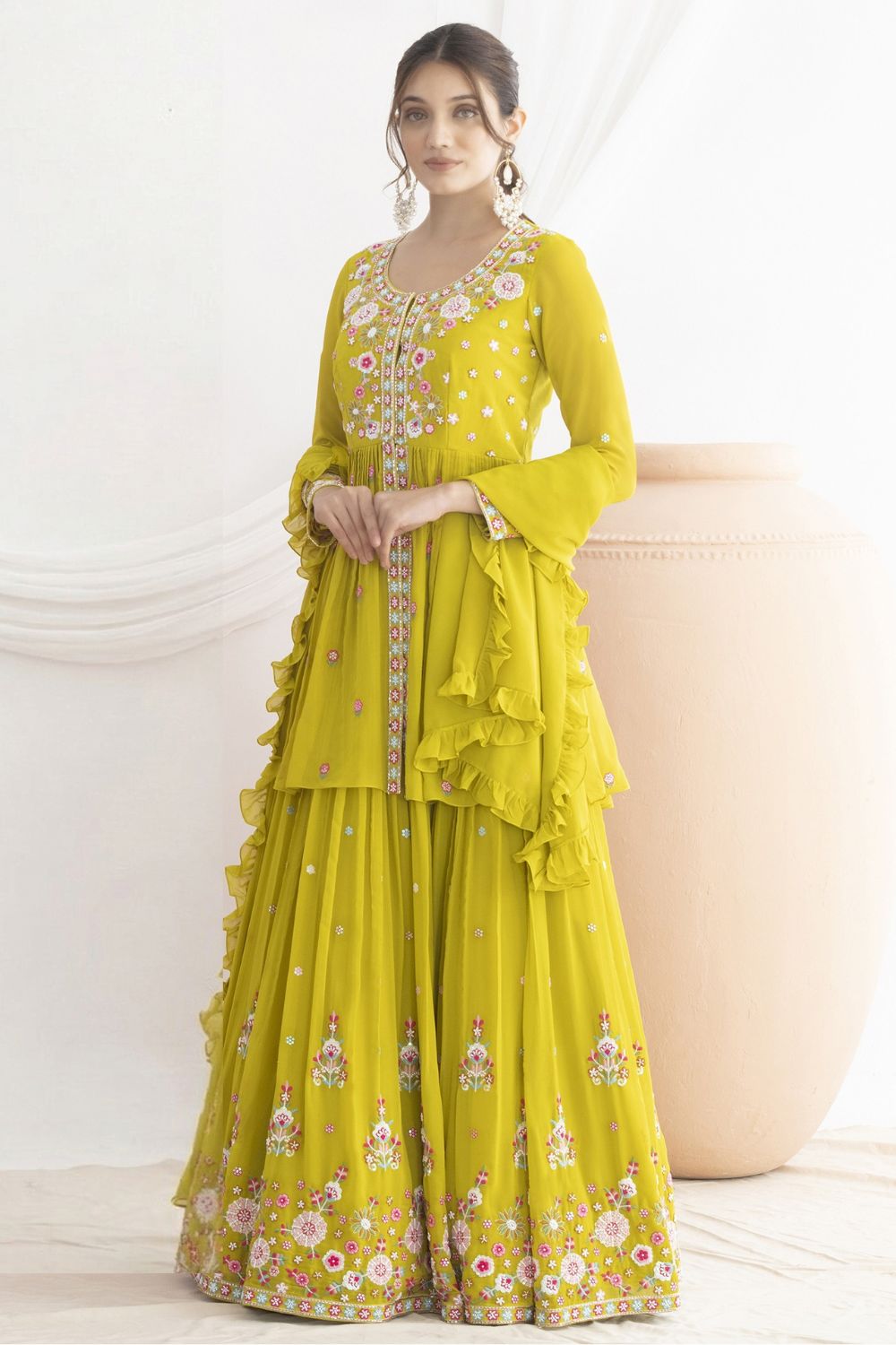 Woman wearing a yellow embroidered haldi traditional outfit on a white background