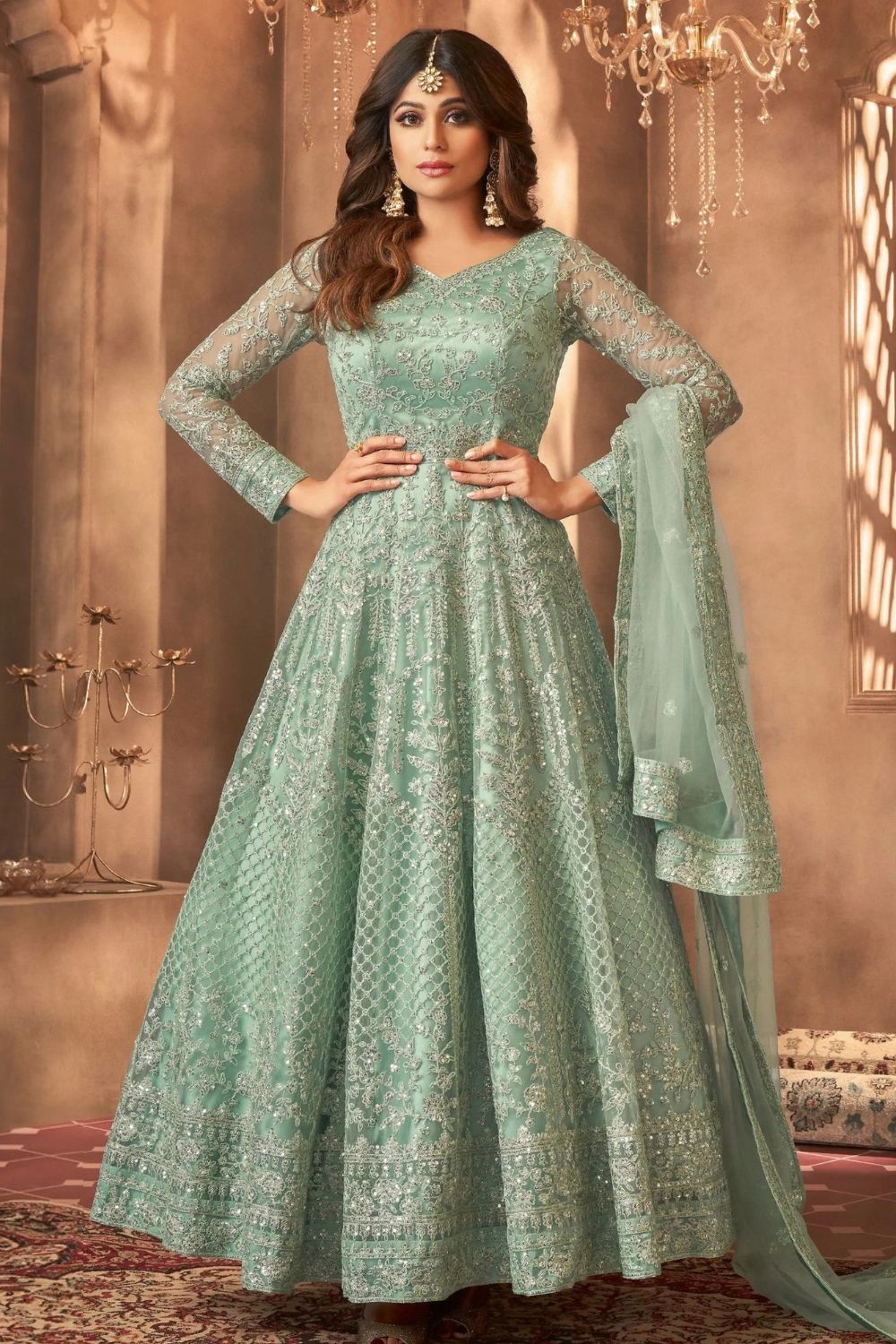 A woman poses in a full-length portrait wearing an embroidered light green anarkali suit with a matching dupatta, an elegant choice among mehndi outfits for guests.