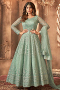 A woman poses in a full-length portrait wearing an embroidered light green anarkali suit with a matching dupatta, an elegant choice among mehndi outfits for guests.