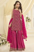 Full-length side view of a reddish pink wedding gharara suit in georgette with Swarovski, Zarkan and embroidery work, dupatta draped.
