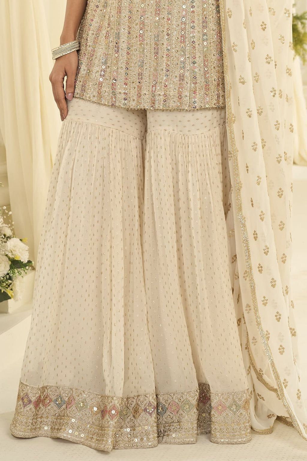 Waist-down view of a cream gharara dress for wedding in georgette with Swarovski and embroidery work on the woven jacquard gharara.