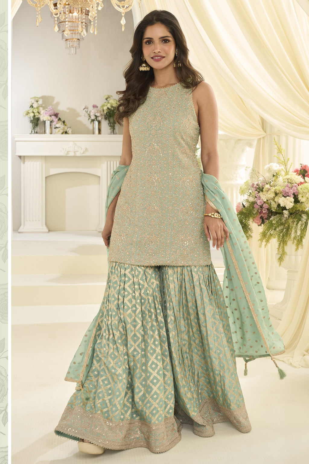Full-length side view of a mint green party wear gharara suit in georgette with Swarovski, Zarkan and embroidery work, dupatta draped.