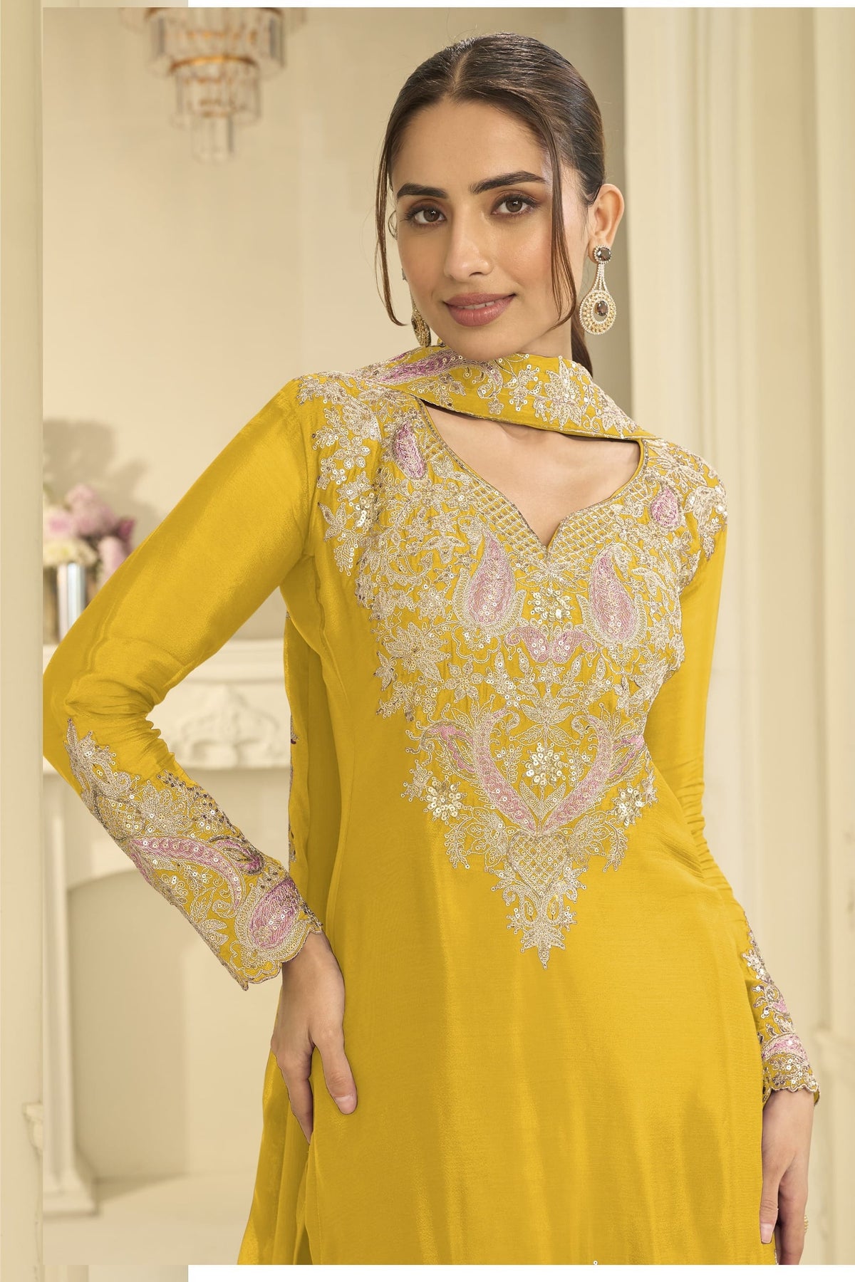 Close-up of a yellow clothes for diwali plazo suit bodice in chinon silk with thread and sequin embroidery on the neckline and sleeves.