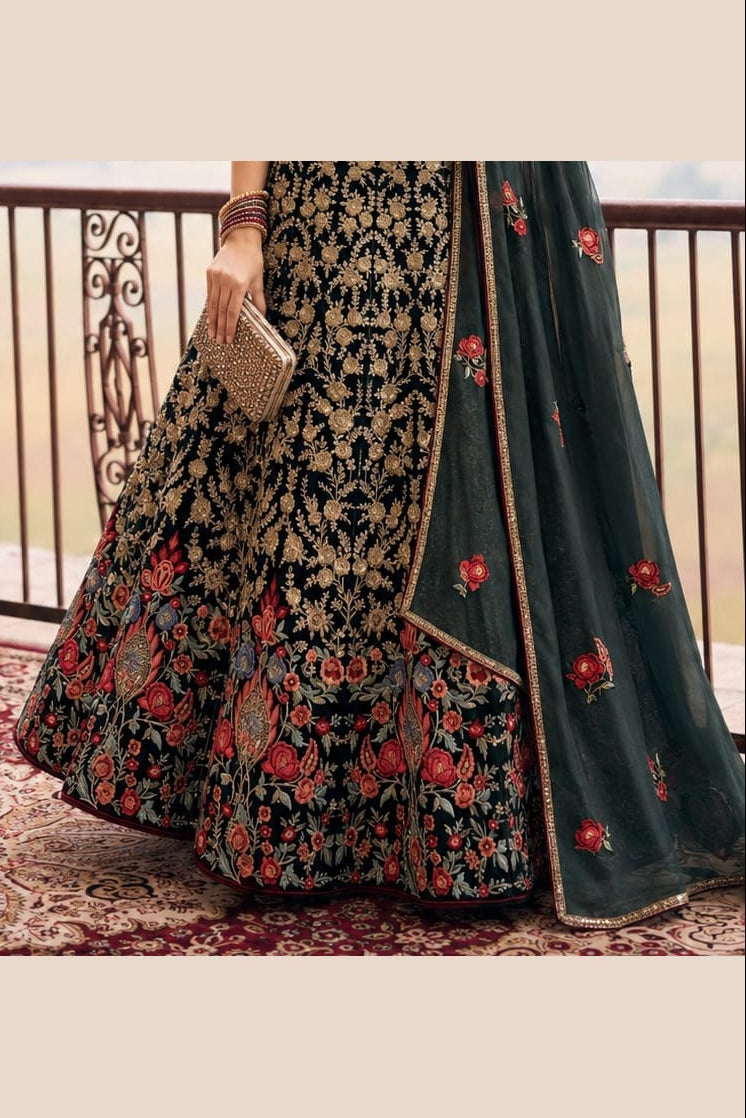Lower view of a dark green ladies party wear lehenga with an embroidered net lehenga skirt and matching net dupatta drape.