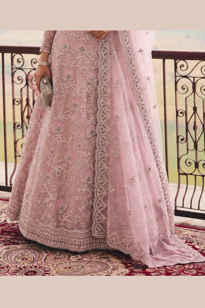 Lower view of a baby pink lehenga for wedding reception with an embroidered net lehenga skirt and matching net dupatta drape.