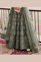 Lower view of a sage green punjabi lehenga for wedding with embroidered net lehenga skirt and matching net dupatta drape.