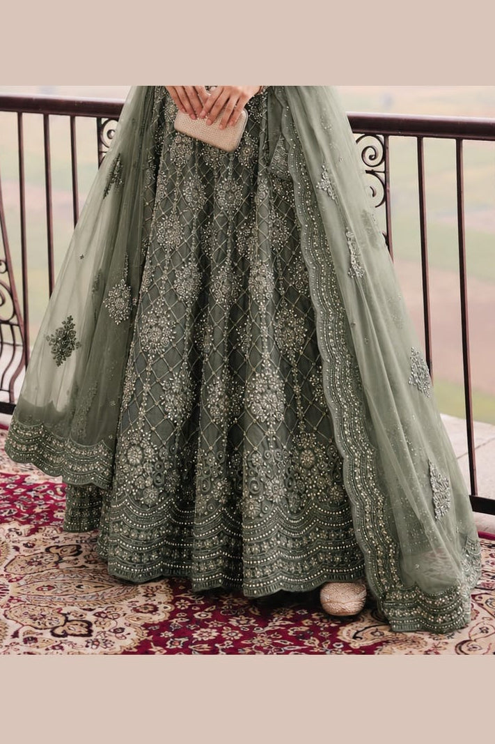 Lower view of a sage green punjabi lehenga for wedding with embroidered net lehenga skirt and matching net dupatta drape.
