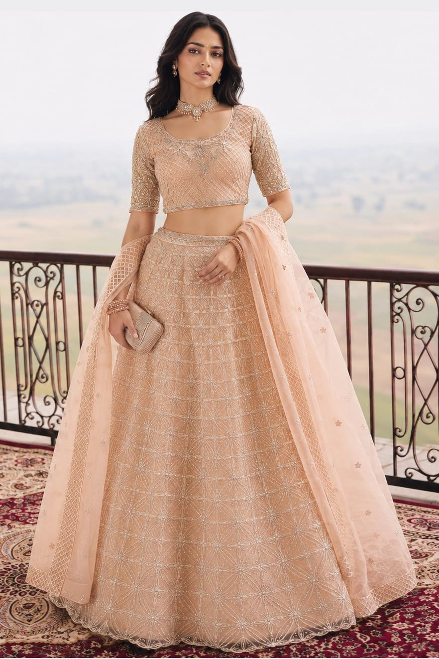 Woman wearing a peach lehenga for wedding women with embroidery work, half sleeve round neck net choli, full-length front view.