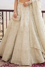 Lower view of an off white wedding reception lehenga with embroidered net lehenga skirt and matching dupatta drape. All-over embroidery.