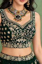 Closeup of the blouse of a dark green lehenga for mehendi, showing the sweetheart neckline and zari, sequin and thread work in detail.
