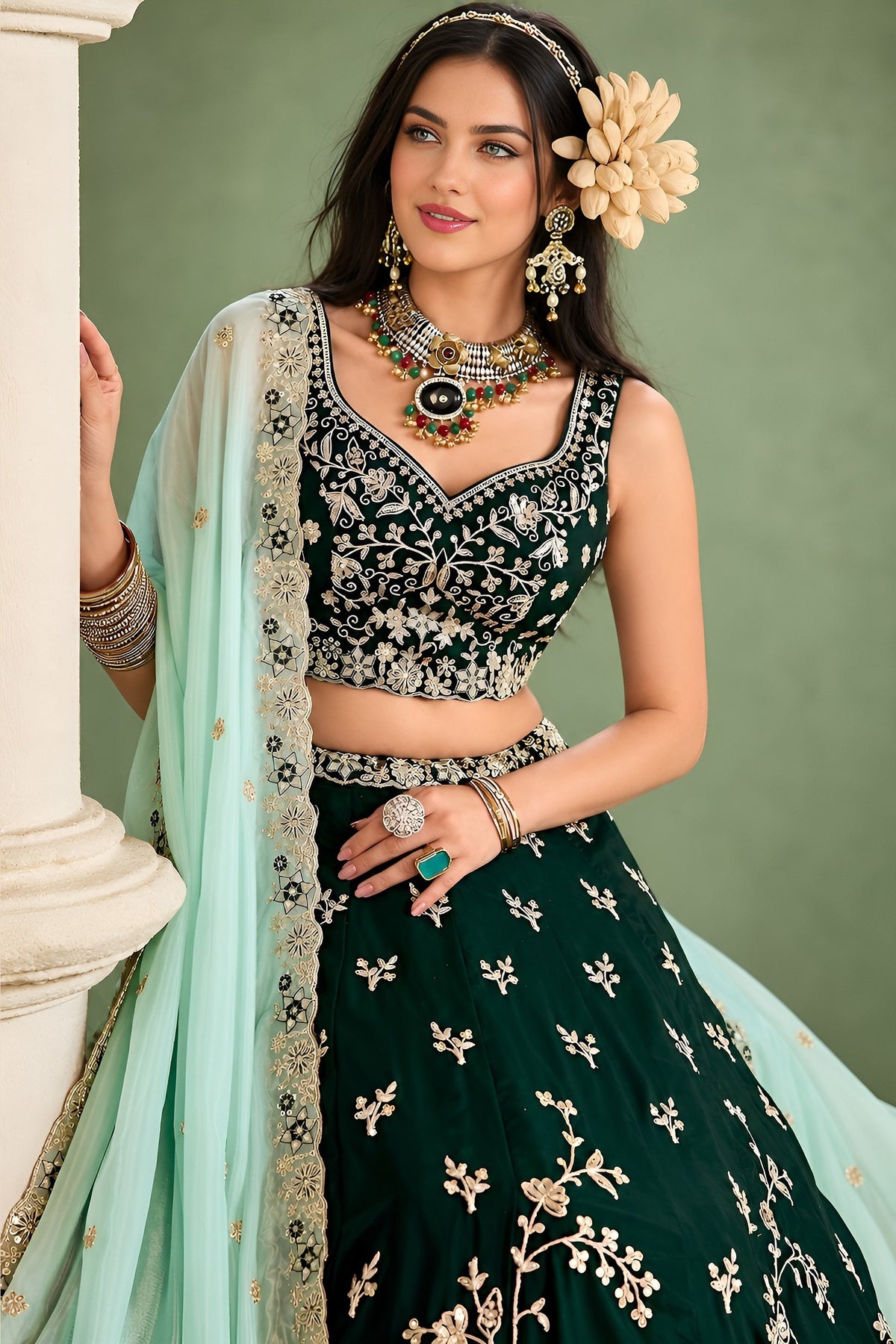 Half view of a dark green mehendi lehenga showing the sweetheart neckline, the flared skirt and the mint dupatta draped elegantly.