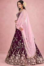 Side view of a maroon wedding reception lehenga showing the flare of the rangoli silk skirt and the light pink dupatta draped over one arm.