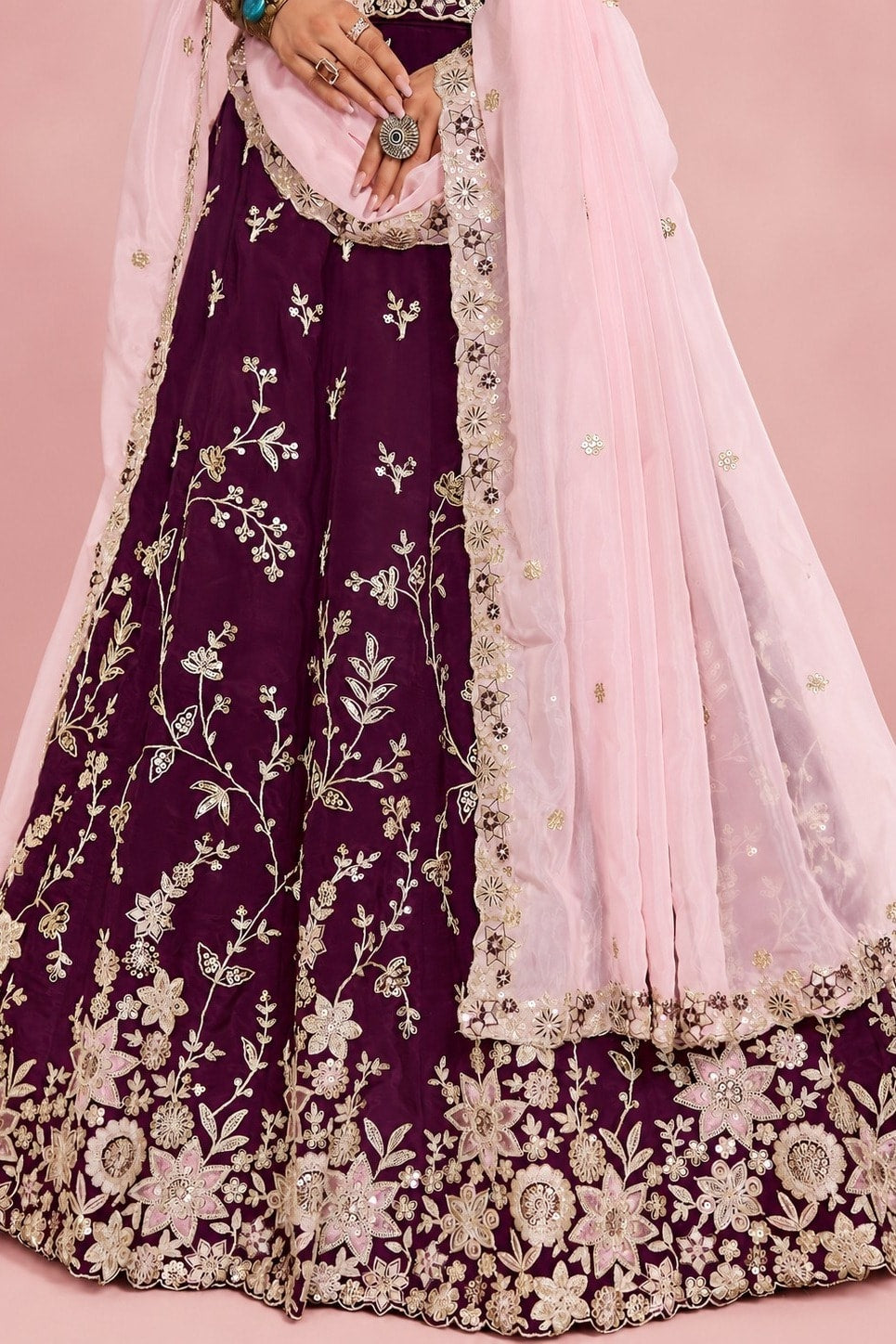 Waist-down closeup of a maroon lehenga for marriage reception, showing the flared rangoli silk skirt and its detailed work.