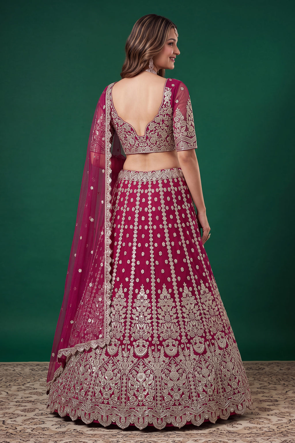 Alternate view of a hot pink party wear lehenga in net with zari, dori and sequins work on the sleeveless blouse and lehenga.