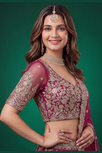 Full-length back view of a hot pink reception lehenga in net with an open back blouse with dori tie and zari and sequins work.