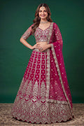 Full-length side view of a hot pink engagement dresses for women lehenga in net with zari, dori and sequins work on the flared skirt.