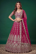 Full-length side view of a hot pink engagement dresses for women lehenga in net with zari, dori and sequins work on the flared skirt.