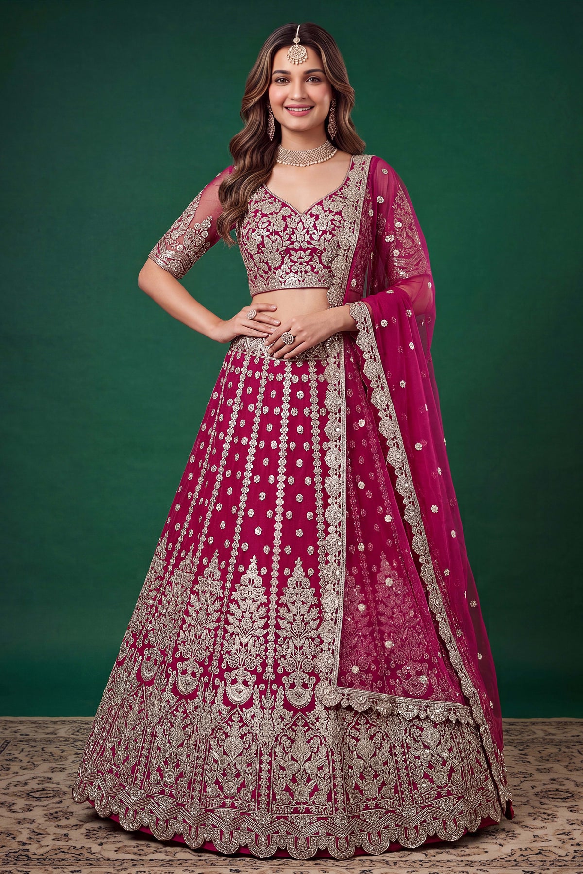 Full-length side view of a hot pink engagement dresses for women lehenga in net with zari, dori and sequins work on the flared skirt.