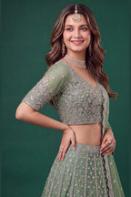 Full-length back view of a pista mehndi outfits lehenga in net with an open back blouse with dori tie and zari and sequins work.
