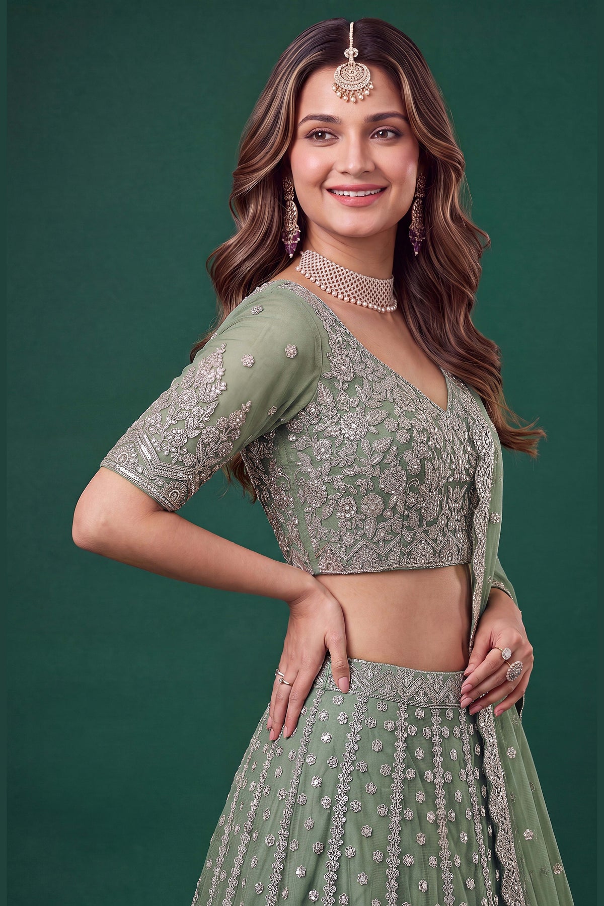 Full-length back view of a pista mehndi outfits lehenga in net with an open back blouse with dori tie and zari and sequins work.