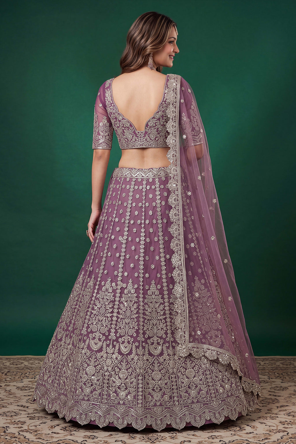 Full-length back view of a light purple sangeet lehenga in net with an open back blouse with dori tie and zari and sequins work.