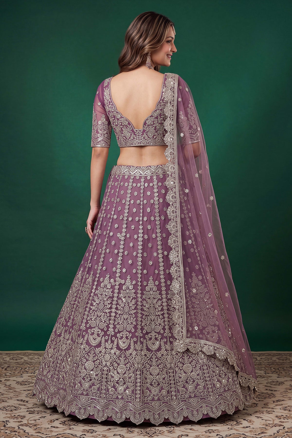 Full-length back view of a light purple sangeet lehenga in net with an open back blouse with dori tie and zari and sequins work.