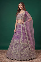 Seated view of a light purple engagement lehenga in net with zari, dori and sequins work on the sleeveless blouse and lehenga.