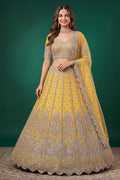 Woman wearing a mustard yellow haldi outfits lehenga in net with zari, dori and sequins work, sleeveless blouse, full-length front view.