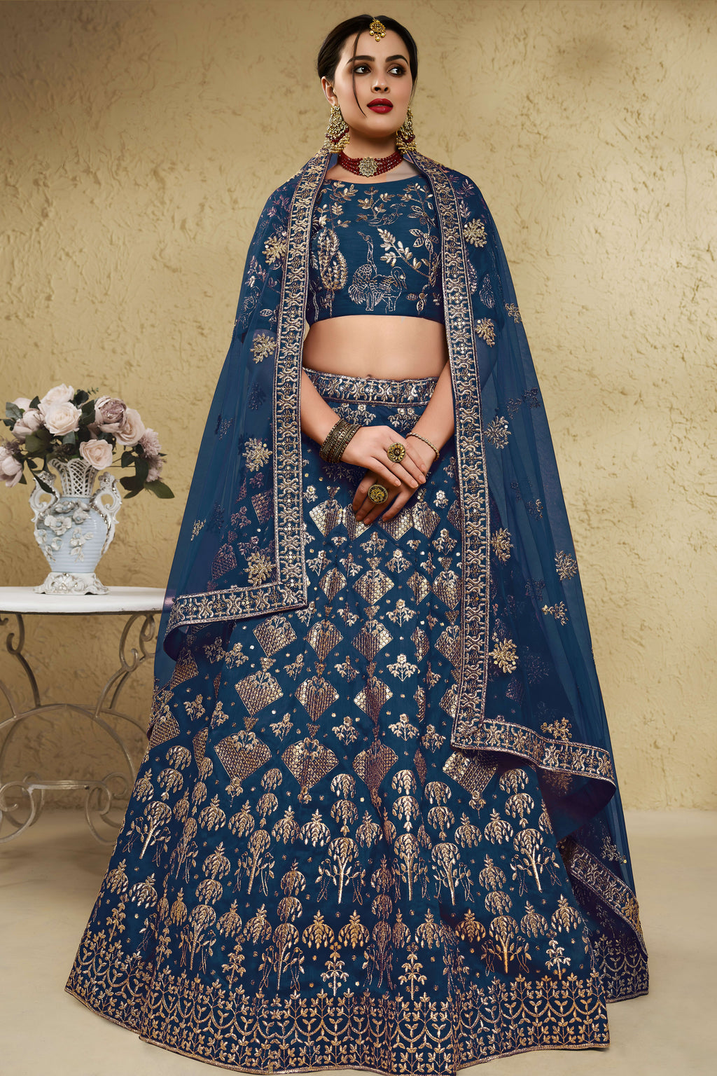 Woman wearing a blue sangeet lehenga in art silk with zari and sequin embroidery, half sleeve boat neck blouse, full-length front view.