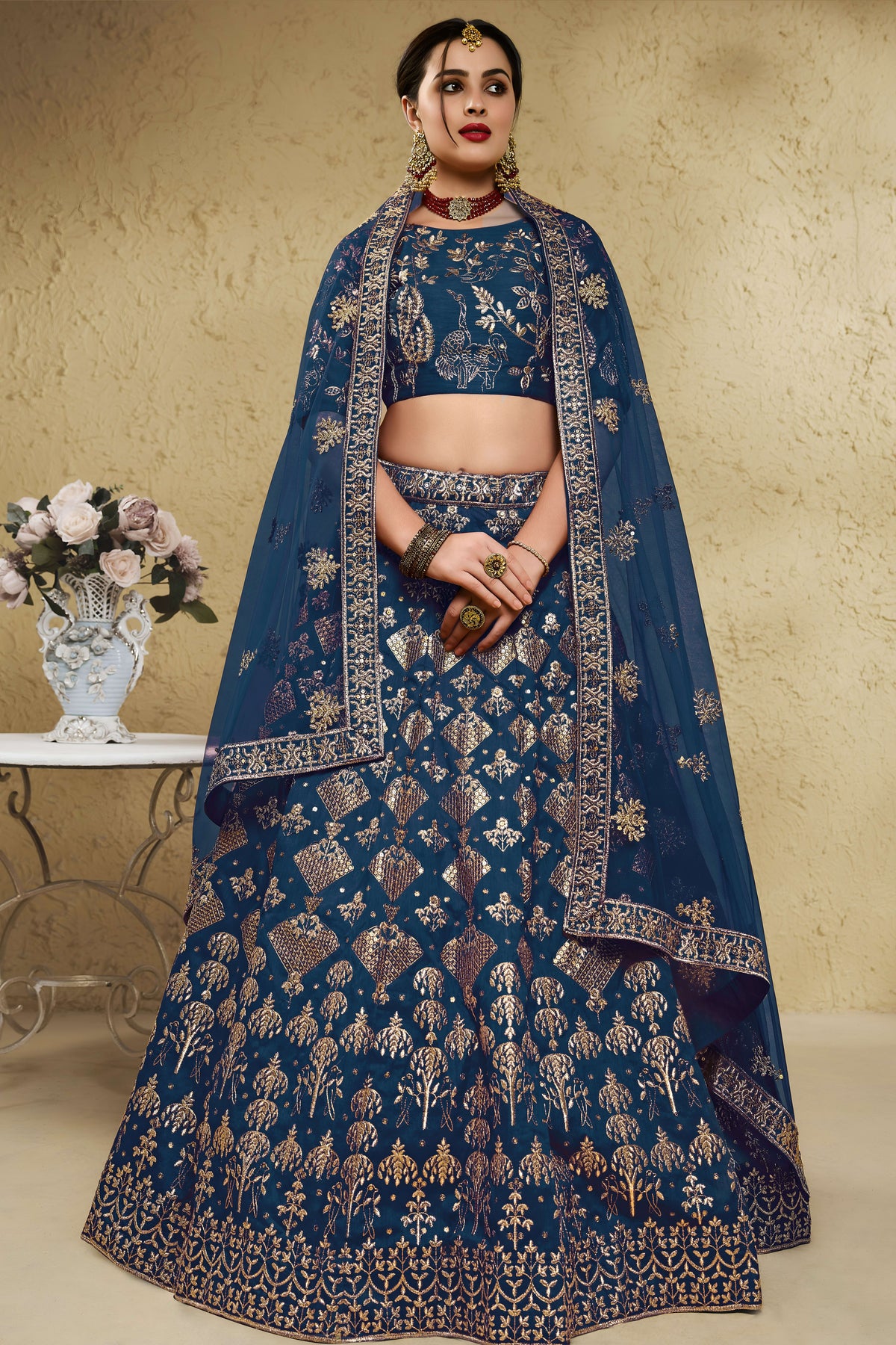 Woman wearing a blue sangeet lehenga in art silk with zari and sequin embroidery, half sleeve boat neck blouse, full-length front view.