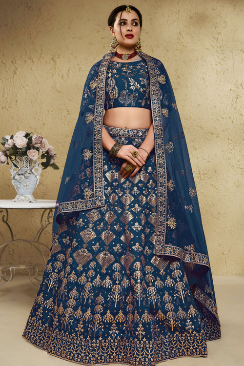 Woman wearing a blue sangeet lehenga in art silk with zari and sequin embroidery, half sleeve boat neck blouse, full-length front view.