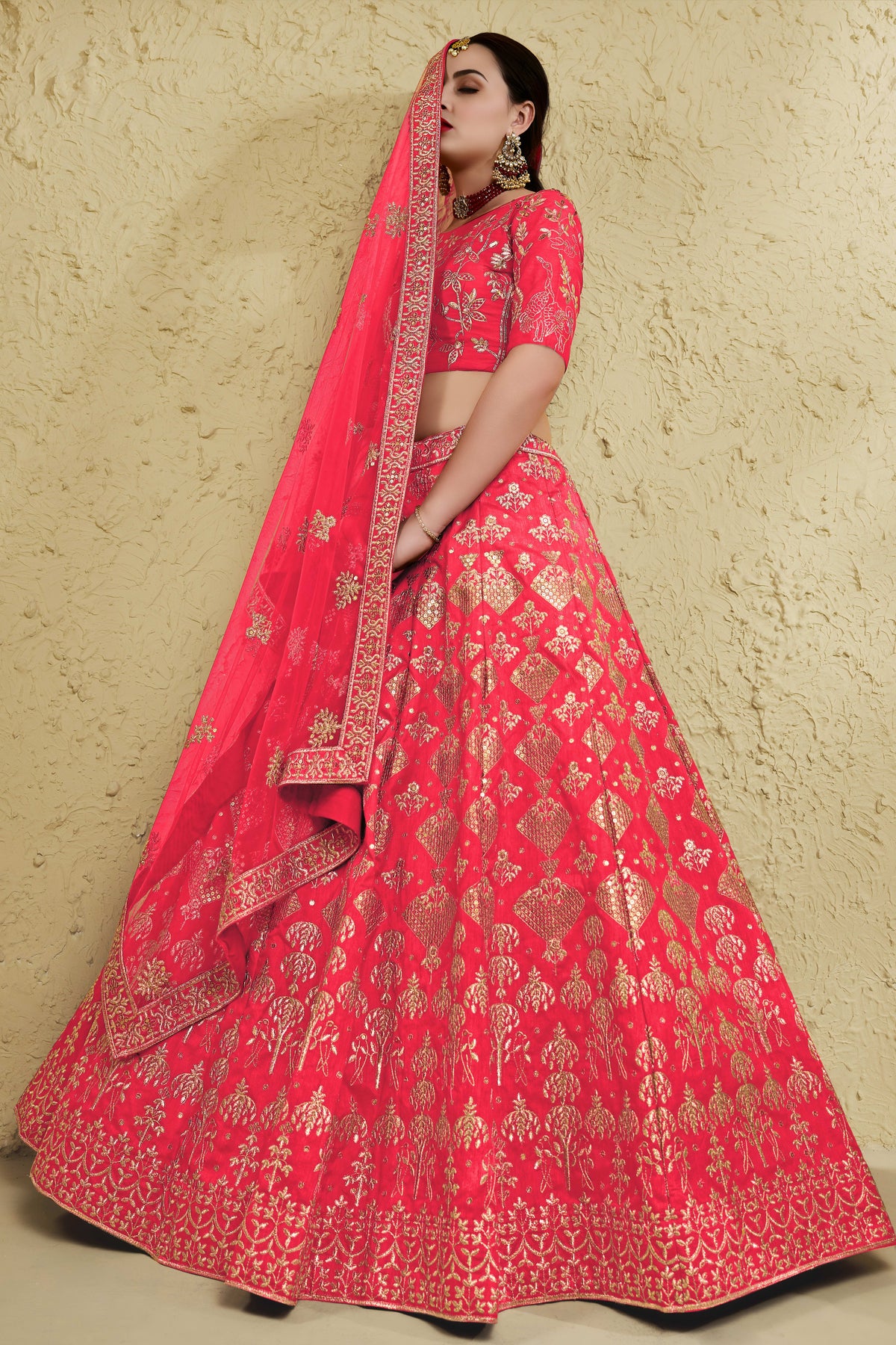Full-length side view of a pinkish red engagement dresses for women lehenga in art silk with zari and sequin embroidery work on the flared skirt.