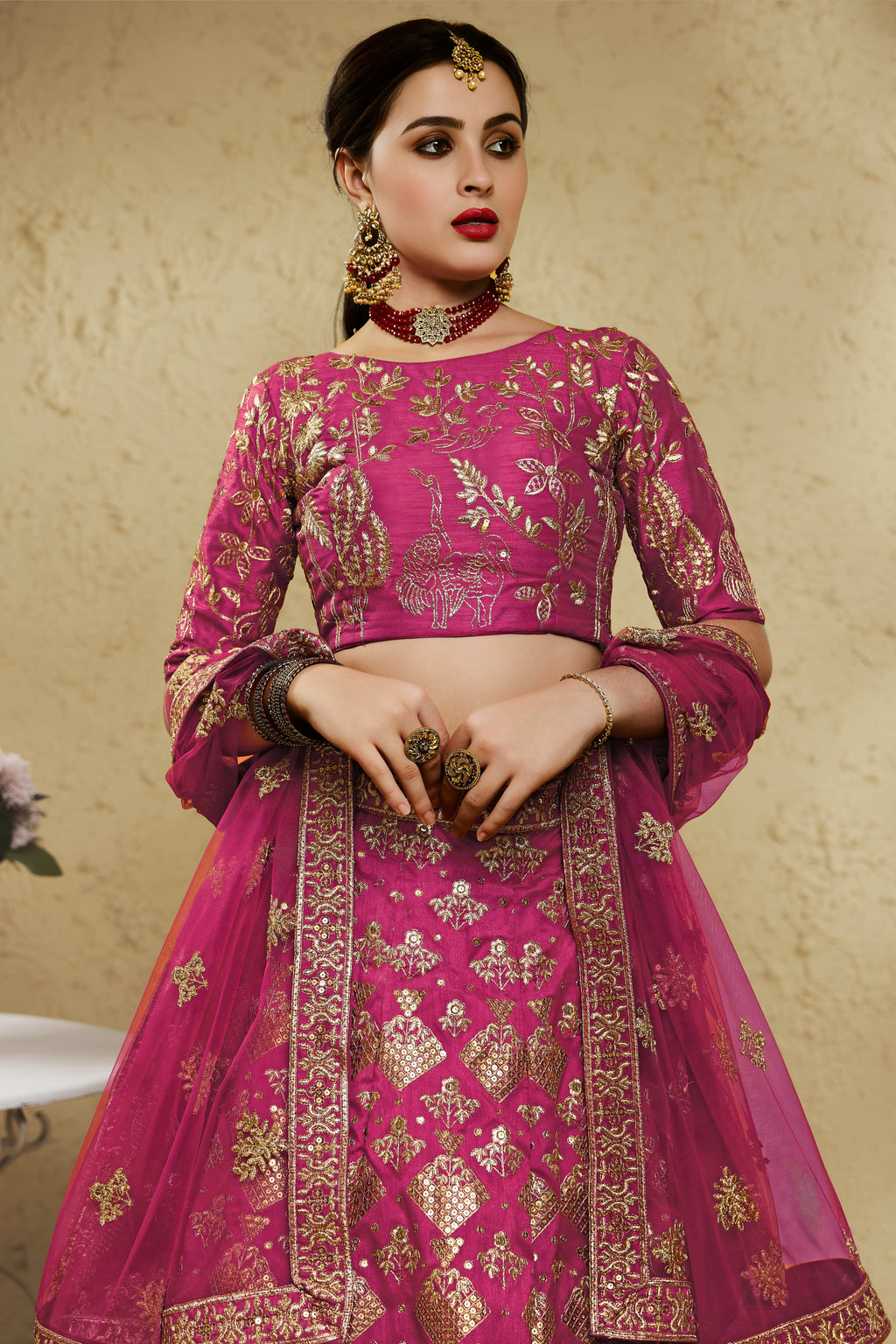 Close-up view of a dark pink reception lehenga in art silk with detailed zari and sequin embroidery work on the blouse and lehenga skirt.
