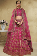 Woman wearing a dark pink reception lehenga in art silk with zari and sequin embroidery, half sleeve boat neck blouse, full-length front view.