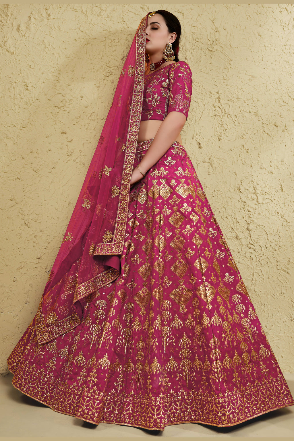 Full-length side view of a dark pink engagement dresses for women lehenga in art silk with zari and sequin embroidery work on the flared skirt.