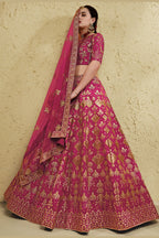 Full-length side view of a dark pink engagement dresses for women lehenga in art silk with zari and sequin embroidery work on the flared skirt.