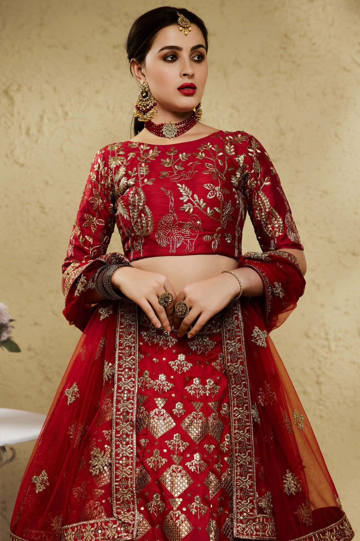 Close-up view of a red engagement lehenga in art silk with detailed zari and sequin embroidery work on the blouse and lehenga skirt.