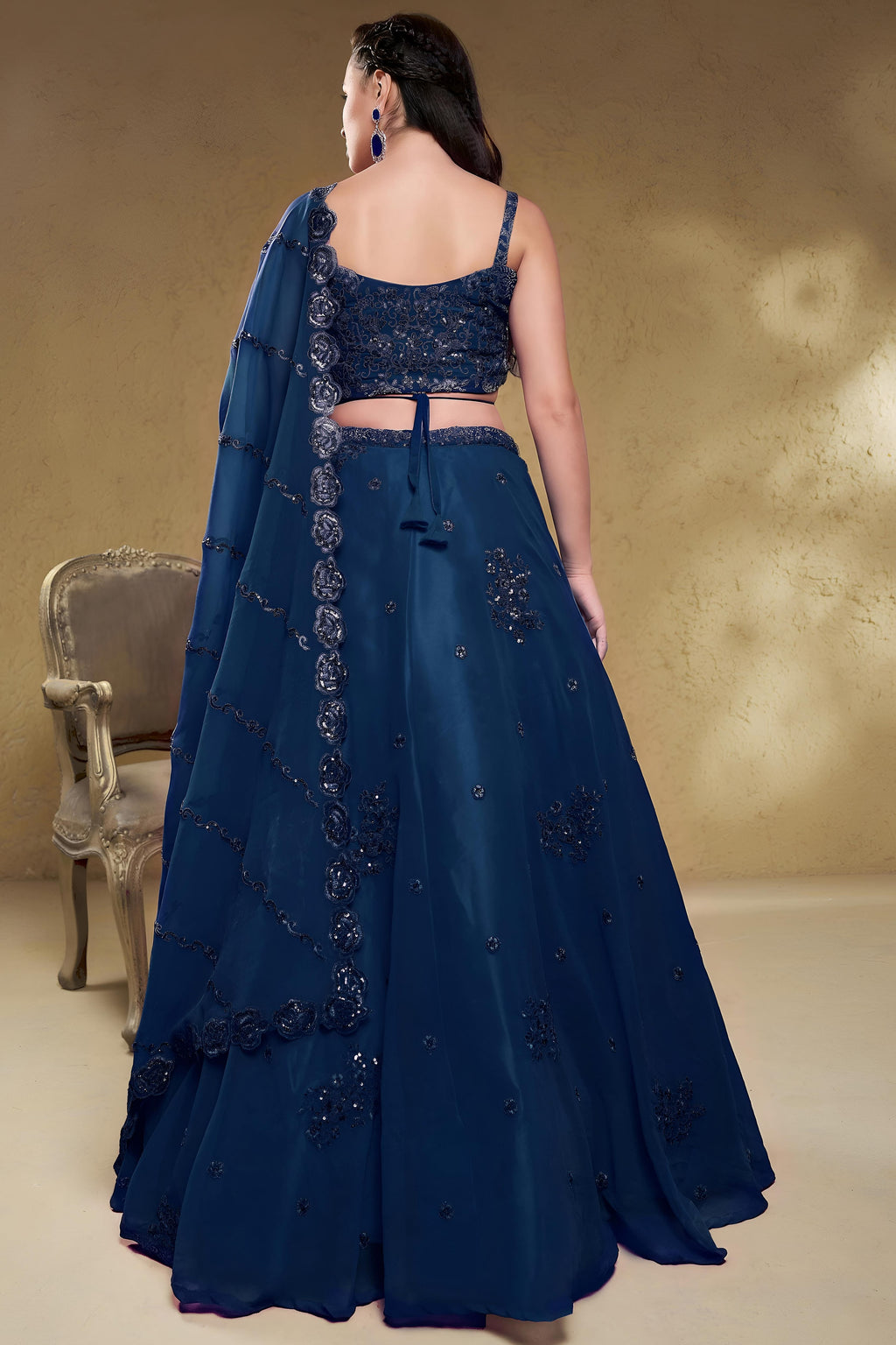 Full-length back view of a blue sangeet lehenga in georgette with an open back blouse with dori tie and zari and sequin work.