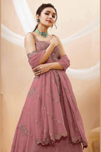 Seated view of a rust pink engagement lehenga in georgette with zari, dori and sequin work on the sleeveless blouse and lehenga.