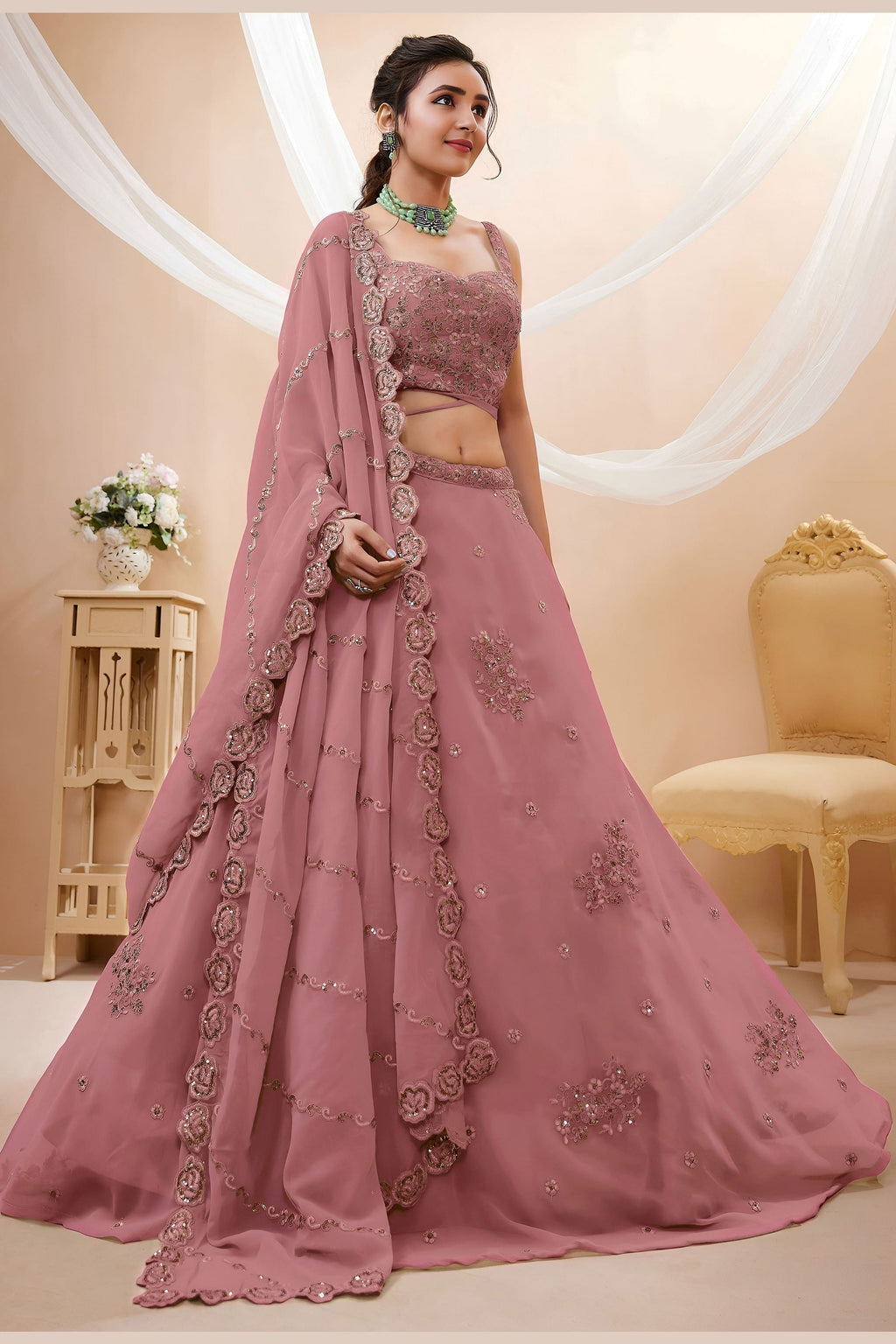 Full-length side view of a rust pink reception lehenga in georgette with zari, dori and sequin work on the flared lehenga skirt.